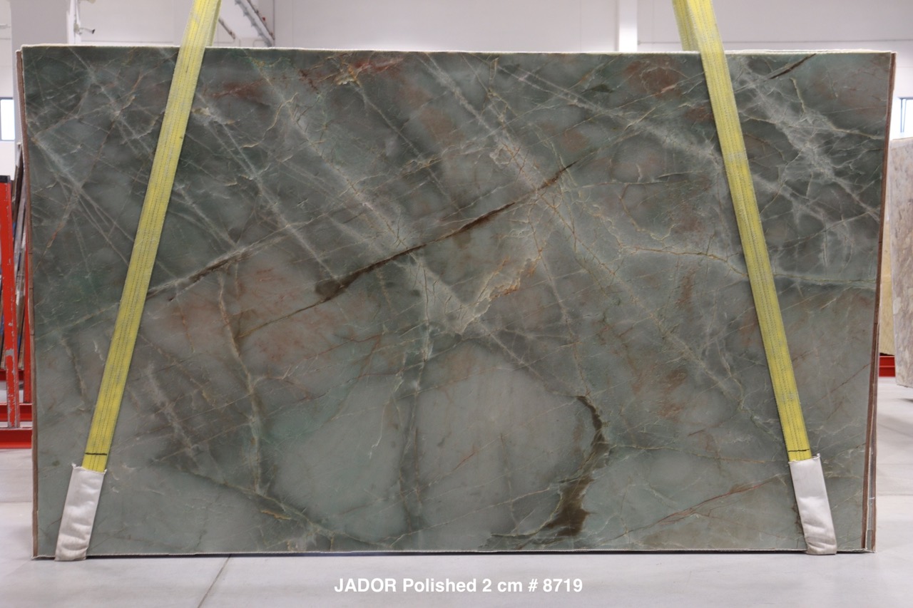 Jadore quartzite slab with translucent jade-green field crossed by rust and copper veining, polished, photographed at the factory