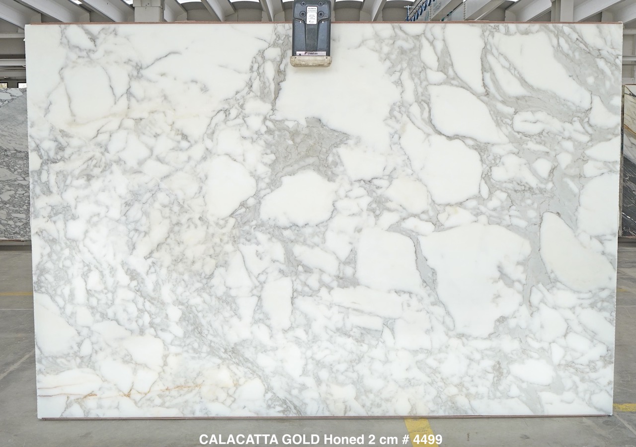 Calacatta Gold marble slab with white field, soft grey veining and warm gold accents, honed, photographed at the factory