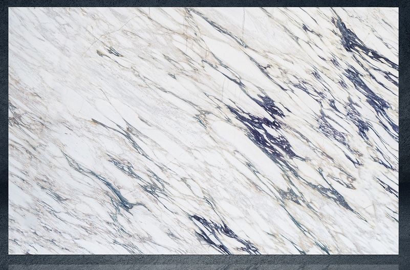 Calacatta marble slab with white field crossed by diagonal blue and charcoal veining and warm gold accents