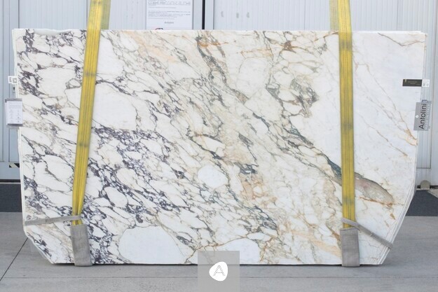 Antolini marble slab with white field, warm gold veining, and charcoal-violet currents