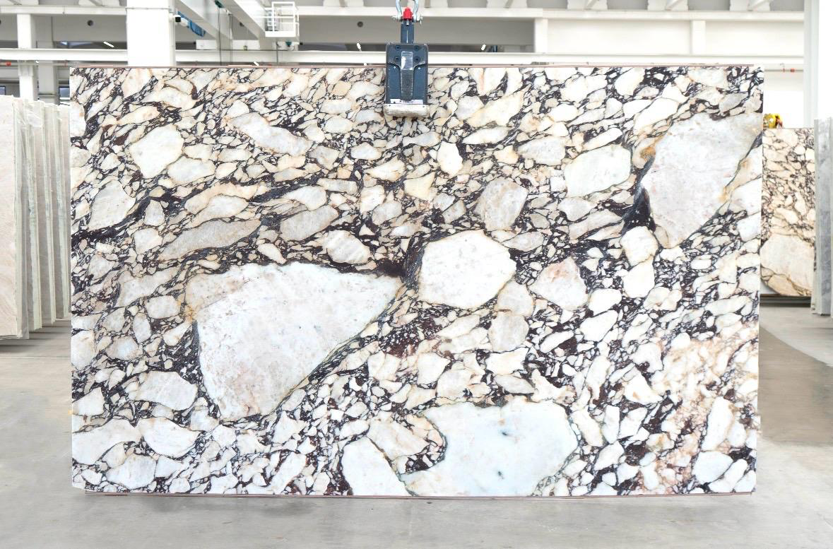 Calacatta Viola Brecciato marble slab with white field, oxblood and violet network veining, photographed at the factory