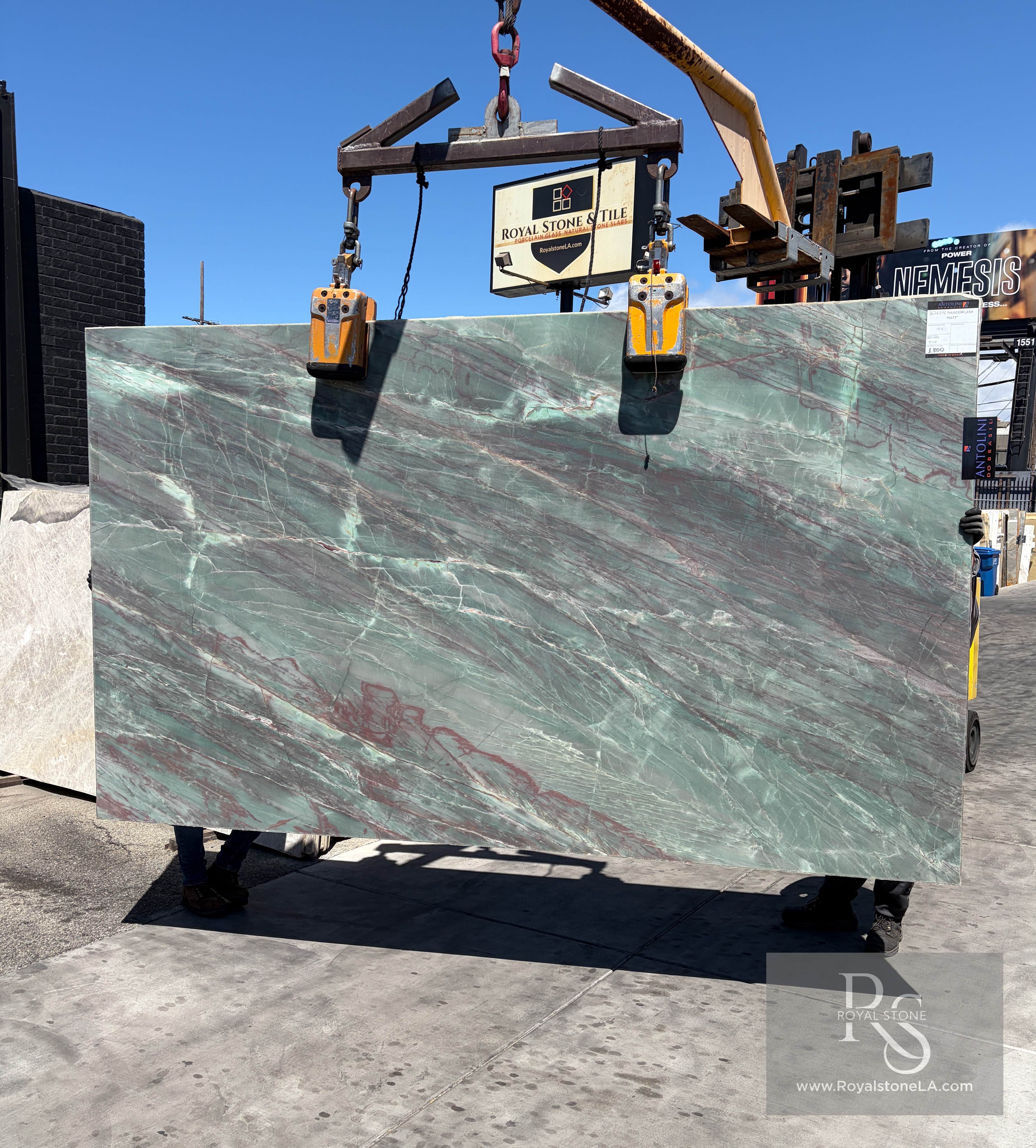 Antolini Thunderflash green quartzite slab, 2cm honed, 76 by 129 inches, with matte seafoam-green field and softened garnet and copper veining, hanging from a crane at the Royal Stone & Tile Los Angeles yard