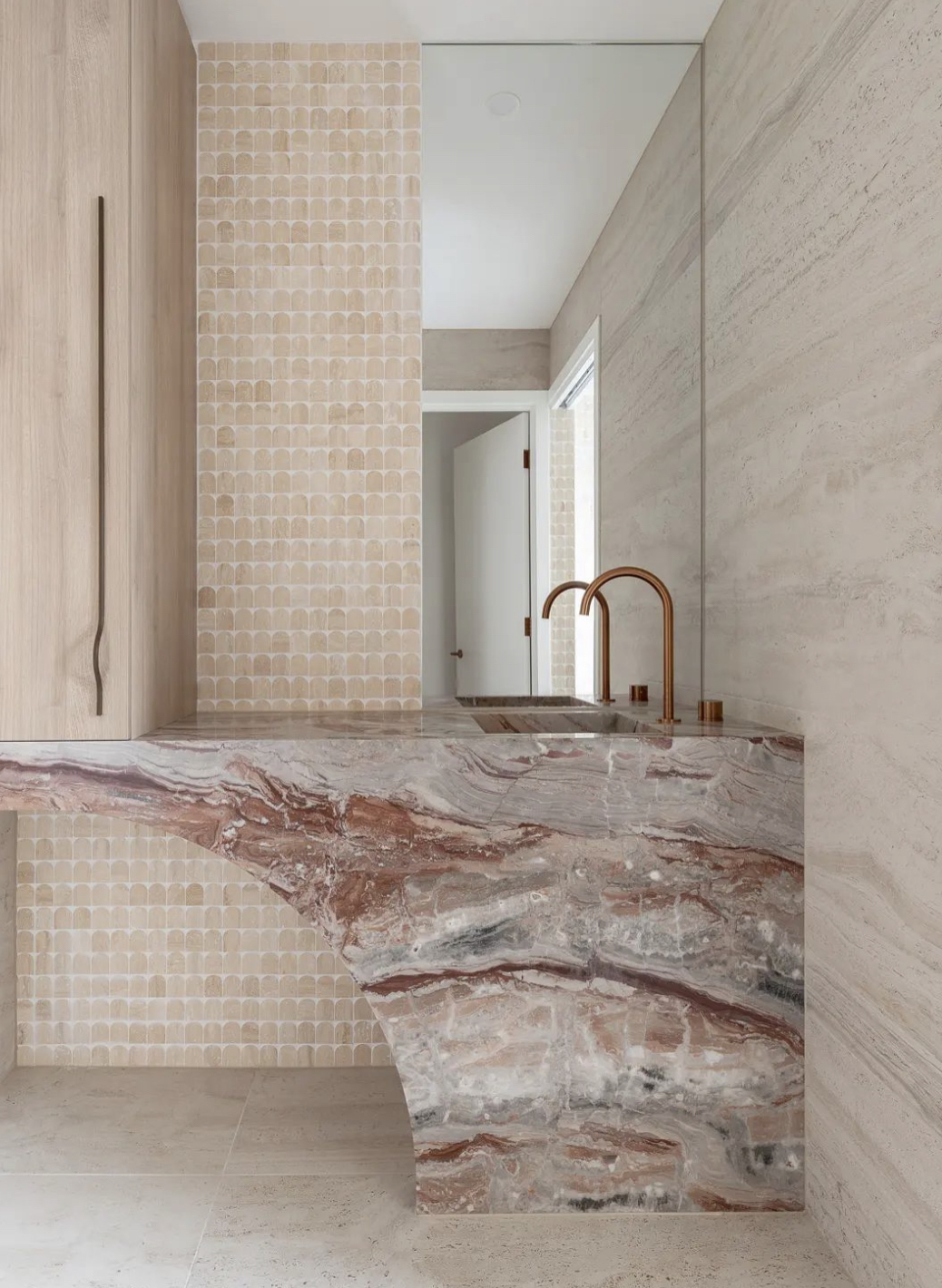 Viola Orobico marble carved into a sculptural powder room vanity with travertine wall and arched mosaic tile surround