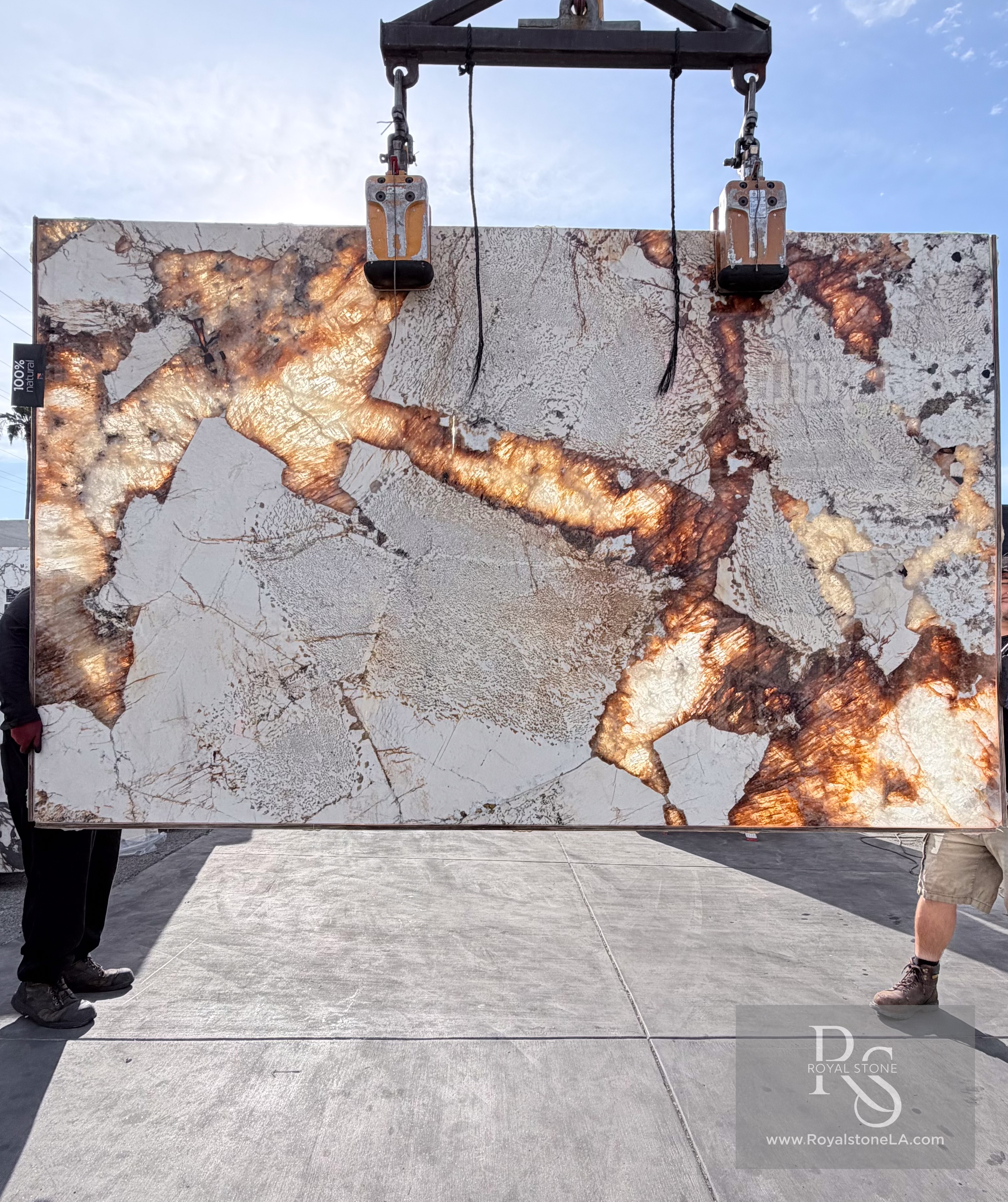 Antolini Patagonia Original Unique quartzite slab, 2cm polished, 75 by 121 inches, with translucent ivory plates fractured by molten copper and amber veining, backlit and hanging from a crane at the Royal Stone & Tile Los Angeles yard